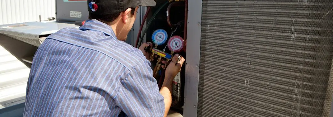 HVAC technician servicing a condenser unit in Eagle Pass